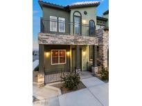 Two-story townhome featuring stone accents, a balcony, and a covered front porch at 6447 Wide Sky St, Las Vegas, NV 89166