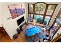 Bright living room with a pool table, floor-to-ceiling windows, and view of the outdoor swimming pool at 129 S Ring Dove Dr, Las Vegas, NV 89144