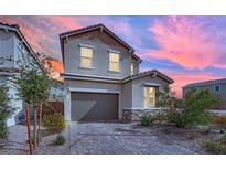 Inviting two-story home with a two-car garage and a beautifully paved driveway at sunset at 393 Desert Cadence St, Henderson, NV 89011