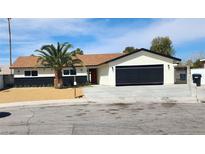 Charming single-story home featuring a black garage door, a beautiful palm tree and a well-maintained lawn at 3991 Shadow Wood Ave, Las Vegas, NV 89121