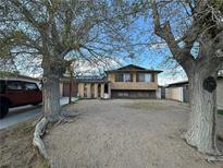 Two-story home featuring a stucco exterior, mature trees, and desert landscaping at 6340 Factor Ave, Las Vegas, NV 89107