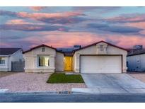 Charming single-story home with a two-car garage, xeriscaped yard and blue, pink and yellow clouds in the sky at 3874 Cinnamonwood Way, Las Vegas, NV 89115