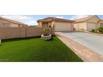 Well-maintained front yard with artificial grass, brick-paved driveway and walkway leading to a two-car garage at 4611 Julesburg Dr, Las Vegas, NV 89139
