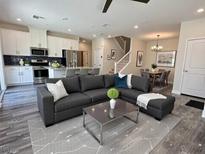 Bright living room open to dining and kitchen, features modern gray sofa and updated flooring at 545 Thea St # 1315, Henderson, NV 89052