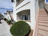 Exterior angle of a multi-level condo with stairs and a sidewalk with green bushes and a door on the first level at 5650 E Sahara Ave # 1035, Las Vegas, NV 89142