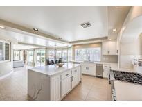 Bright kitchen features an island with white cabinets, tile flooring, and stainless steel appliances at 11072 Pentland Downs St, Las Vegas, NV 89141