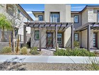 Contemporary two-story home with a decorative pergola, stone accents, and stylish front yard landscaping at 11705 Bearpaw Meadow Ave, Las Vegas, NV 89138