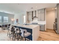 Bright kitchen features an island with bar seating, stainless steel appliances, and light gray cabinetry at 10239 Meandering Dell Ave, Las Vegas, NV 89166