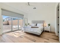 Bright main bedroom features a large sliding glass door, wood flooring and neutral tones at 10239 Meandering Dell Ave, Las Vegas, NV 89166