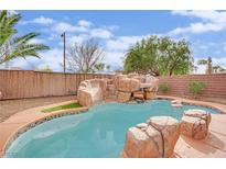Backyard pool featuring rock waterfall, palm trees, and low-maintenance landscaping at 3221 Birdwatcher Ave, North Las Vegas, NV 89084
