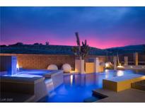 Inviting pool with water features, illuminated at night with colorful sunset skies in the background at 80 Glade Hollow Dr, Las Vegas, NV 89135