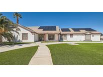 Charming single story home features a lush green lawn, solar panels, and desert landscaping at 8515 Belcastro St, Las Vegas, NV 89113
