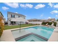 Stunning backyard pool and spa with lounge chairs, striped umbrella, and artificial grass at 2616 Tolmezzo St, Henderson, NV 89044