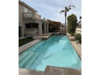 Refreshing backyard pool with a small waterfall feature is set against a neutral-colored stucco home at 7420 Enchanted Hills Ct, Las Vegas, NV 89129