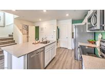 Bright kitchen features stainless appliances, gray countertops, and center island with undermount sink at 6954 Lynbridge St # Lot 56, Las Vegas, NV 89166