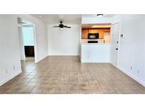 Bright living room features neutral tile flooring, and is adjacent to the kitchen with wood cabinets at 7100 Pirates Cove Rd # 1022, Las Vegas, NV 89145