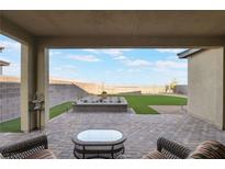 Inviting covered patio overlooks a landscaped backyard with artificial turf and a charming planter box at 10216 Chrysolite Pl, Las Vegas, NV 89143