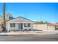 Charming single-story home with a crisp white exterior, blue door, desert landscaping, and a spacious driveway at 1945 Margarita Ave, Henderson, NV 89011