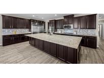 A spacious kitchen features a large center island, stainless steel appliances, and dark cabinetry at 3428 Royal Calloway Ave, Las Vegas, NV 89141