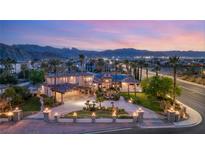 Stunning exterior view of grand estate with palm trees, lush landscaping, and mountain backdrop at sunset at 4775 N Tee Pee Ln, Las Vegas, NV 89129