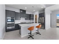Modern kitchen features stainless appliances, quartz countertops, gray cabinets and two sleek orange bar stools at 10158 Super Jovian St, Las Vegas, NV 89143