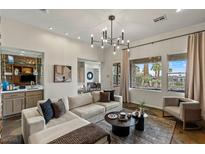 Bright living room featuring a large sectional sofa, modern chandelier, and an open view of the outdoor landscape at 2822 Soft Horizon Way, Las Vegas, NV 89135