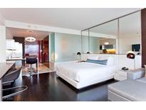 Modern bedroom boasts dark wood floors, comfortable bed, mirrored walls and partially open kitchen at 4381 W Flamingo Rd # 2605, Las Vegas, NV 89103