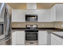 Well-lit kitchen with white cabinetry, stainless steel appliances, and dark countertops at 4685 Apulia Dr # 202, North Las Vegas, NV 89084