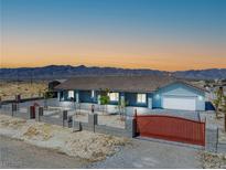 Charming single-story home with a red gate, desert landscaping, and mountain views at 9090 Josepine St, Pahrump, NV 89048