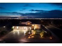 Striking home exterior at night showcasing a three-car garage and professionally landscaped front yard with landscape lighting at 979 Evening Dew Dr, Las Vegas, NV 89110