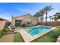 Beautiful backyard pool with artificial turf, palm trees, and lounge chairs provides a peaceful outdoor retreat at 6022 Quintillion Ave, Las Vegas, NV 89122