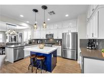 Bright kitchen boasts white cabinets, a blue island, and stainless steel appliances at 69 Via Di Mello, Henderson, NV 89011