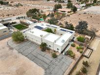 An aerial view of a home with solar panels, a three-car garage, and landscaping, set against a desert backdrop at 3910 W Pebble Rd, Las Vegas, NV 89139