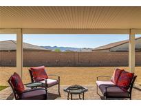 View of back yard and mountains from a covered patio with chairs and firepit at 4801 Westmont Dr, Pahrump, NV 89061