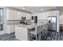 Bright kitchen features white cabinetry, stainless appliances, and granite countertops with an island and barstool seating at 4801 Westmont Dr, Pahrump, NV 89061
