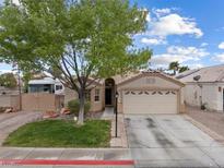 Charming single-story home featuring a two-car garage and well-maintained front yard with mature tree at 5107 Morning Splash Ave, Las Vegas, NV 89131
