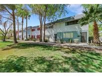 Inviting townhome exterior with mature trees, lush green grass and colorful facade at 703 Greenbriar Townhouse Way, Las Vegas, NV 89121