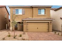 Two-story home with a tan exterior, brown shutters, two-car garage and desert landscaping at 4253 Gold Desert St, North Las Vegas, NV 89032