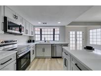 Modern kitchen featuring stainless steel appliances, light grey cabinets, and large bay window for natural light at 5151 Tennis Ct, Las Vegas, NV 89120