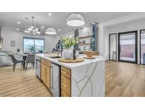 A modern, open-concept kitchen featuring a waterfall island, wine storage, and bright lighting at 154 Nine Mile Creek Dr, Las Vegas, NV 89138
