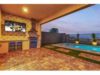 Covered outdoor kitchen, TV, and barbecue area near pool with desert view at 154 Nine Mile Creek Dr, Las Vegas, NV 89138