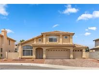 Two-story home with tan stucco exterior, tile roof, brick driveway, and three-car garage at 2716 Timber Crossing Ct, Henderson, NV 89074