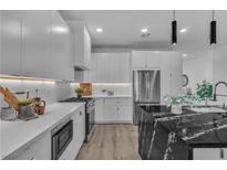 Modern kitchen featuring white cabinets, stainless steel appliances, and a black marble island at 4434 Verdiccio Ave, Las Vegas, NV 89141