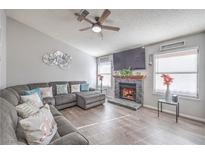 Inviting living room with a stone fireplace, ceiling fan, and lots of natural light at 6408 Deadwood Rd, Las Vegas, NV 89108