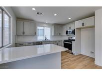 Bright kitchen features a center island, recessed lighting, stainless steel appliances and quartz countertops at 9855 Ashton Pines Ct, Las Vegas, NV 89147