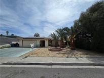 Charming single-story home featuring a desert landscape, mature palm trees, and a covered entryway at 2501 Capistrano Ave, Las Vegas, NV 89121