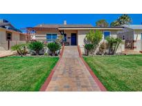 Charming home featuring a well-manicured lawn, mature trees, and a welcoming brick pathway at 516 Arizona St, Boulder City, NV 89005