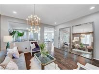 Bright living room features a modern chandelier, hardwood floors, and large decorative mirrors at 5662 Escamilla Rd, Las Vegas, NV 89135