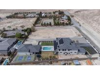 A luxury home features a pool, tennis court, desert landscaping, and ample land for future expansion at 6265 Iron Mountain Rd, Las Vegas, NV 89131