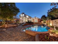Stunning backyard oasis featuring a pristine pool with waterfall and desert landscaping at 8470 S Pioneer Way, Las Vegas, NV 89113